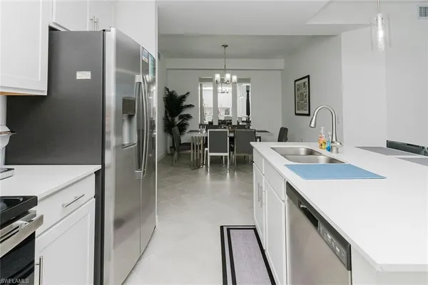 a kitchen with stainless steel appliances kitchen island granite countertop a table chairs microwave and sink