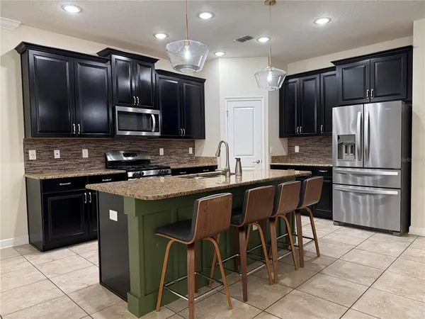 a kitchen with granite countertop wooden cabinets a refrigerator and a stove top oven with wooden floor