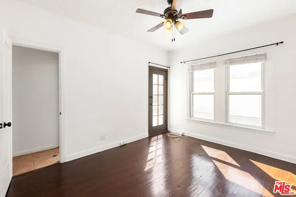an empty room with wooden floor fan and windows