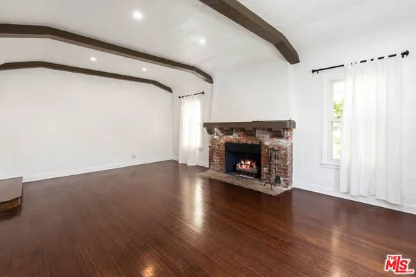 a view of a livingroom with wooden floor and a fireplace