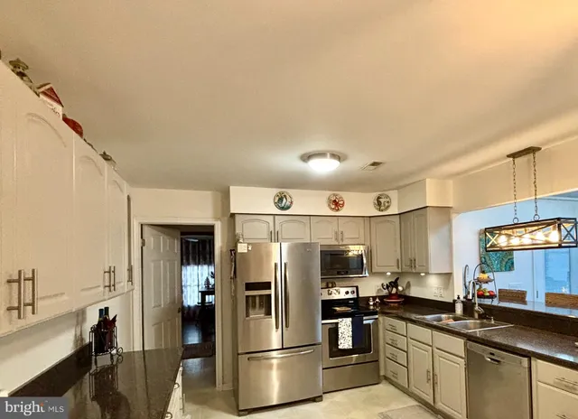 a kitchen with stainless steel appliances a refrigerator a sink a stove a microwave and chairs