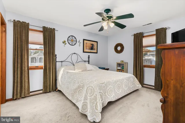 a bedroom with a bed next to a window with a ceiling fan