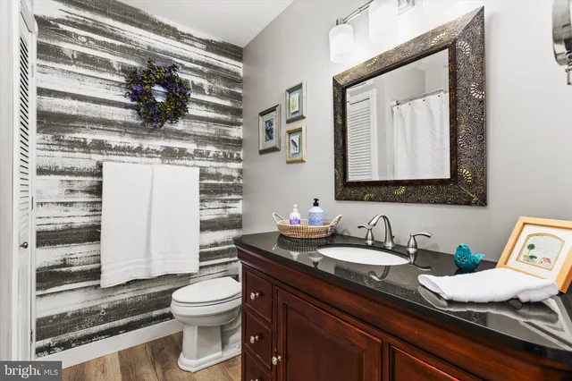 a bathroom with a granite countertop sink a toilet and a mirror