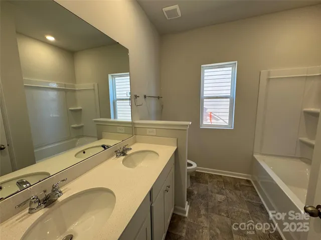 a bathroom with a granite countertop sink a mirror and a bathtub