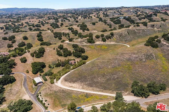 a view of dirt field with trees in background