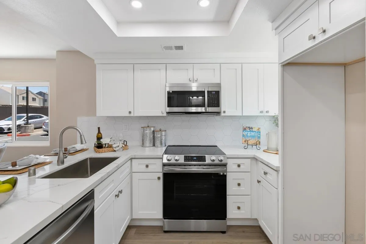 2301 Kings View Circle Spring Valley, CA 91977 - Photo 13 of 26 a kitchen with stainless steel appliances granite countertop a sink a stove a microwave and wooden cabinets
