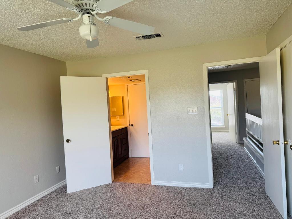 2018 West Rundberg Lane, Unit 12B Austin, TX 78758 - Photo 12 of 16 2nd master bedroom featuring light carpet, a textured ceiling, ensuite bathroom, and ceiling fan