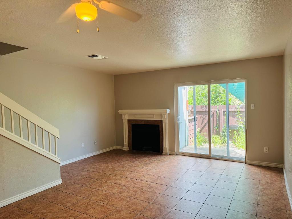 2018 West Rundberg Lane, Unit 12B Austin, TX 78758 - Photo 2 of 16 Unfurnished living room featuring a textured ceiling, stairway, a fireplace, light tile patterned floors, and ceiling fan
