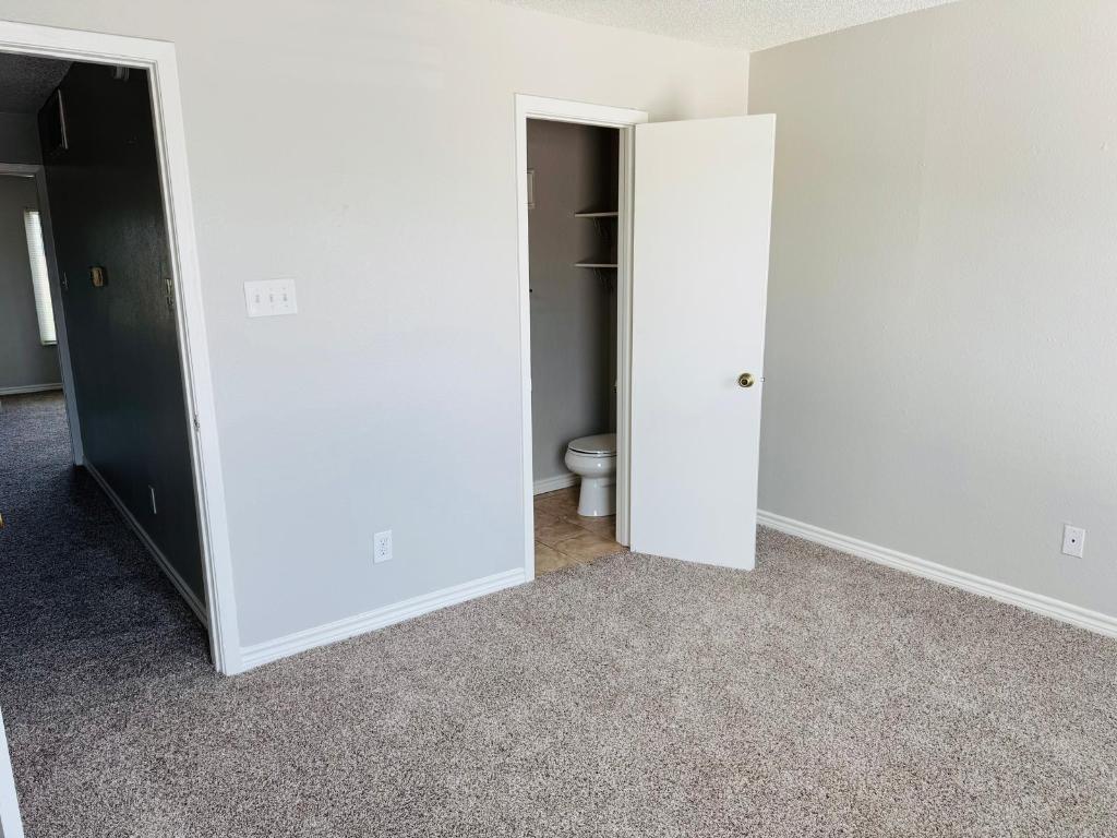2018 West Rundberg Lane, Unit 12B Austin, TX 78758 - Photo 8 of 16 Unfurnished 1st master bedroom featuring light colored carpet, a textured ceiling, and ensuite bath