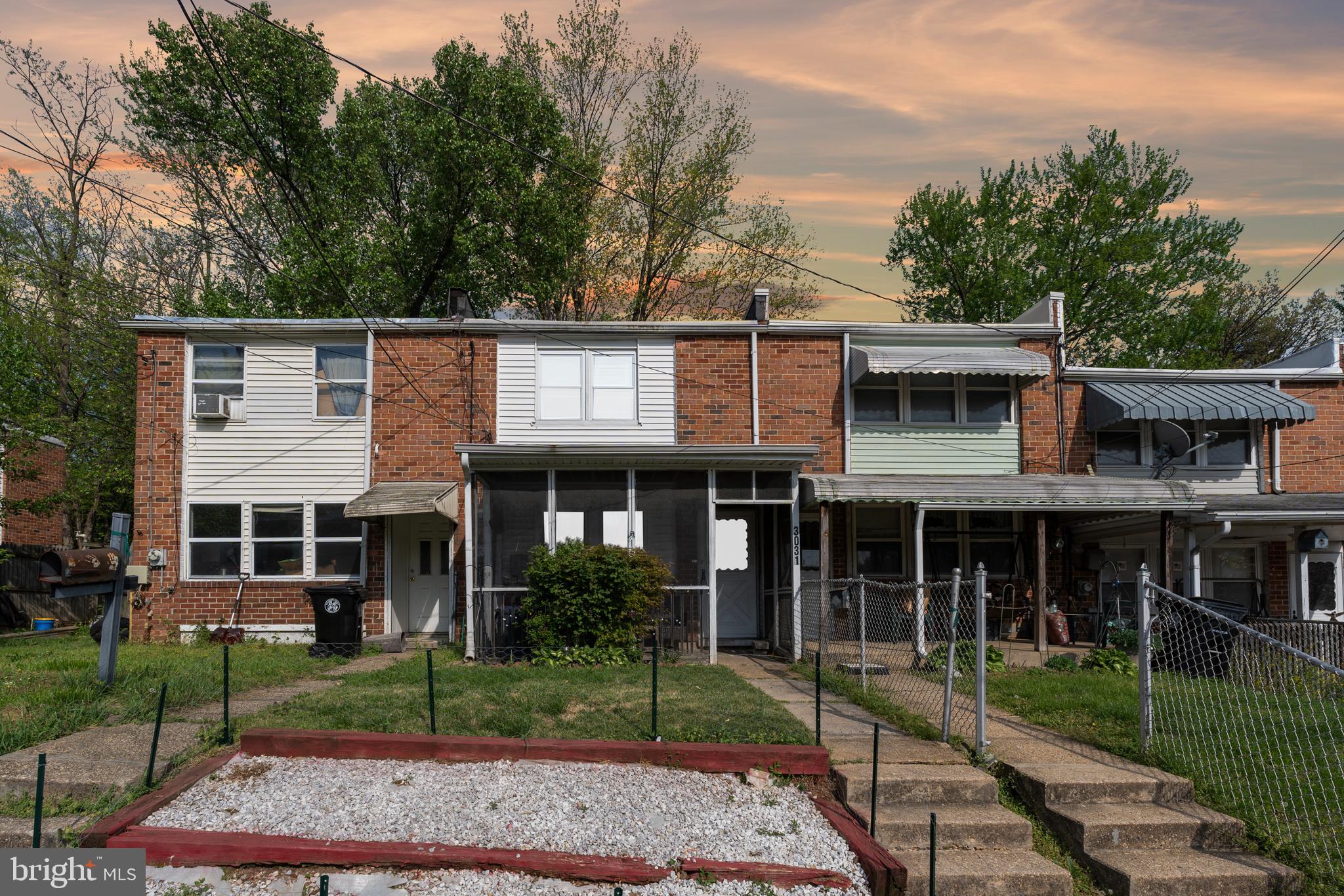 a view of a brick house with large windows and a yard with plants and large trees