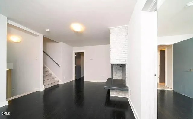 an empty room with wooden floor chandelier fan and windows