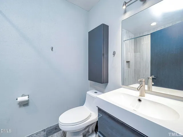 a bathroom with a sink a toilet a mirror and shower