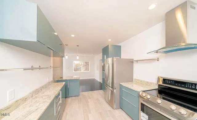 a kitchen with stainless steel appliances granite countertop a refrigerator and a stove top oven