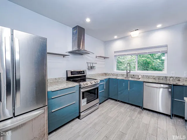 a kitchen with stainless steel appliances granite countertop a stove a sink and a refrigerator
