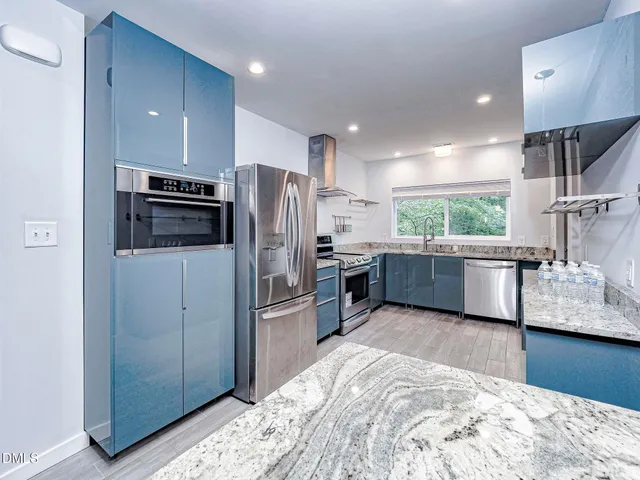 a kitchen with stainless steel appliances kitchen island granite countertop a refrigerator and a sink