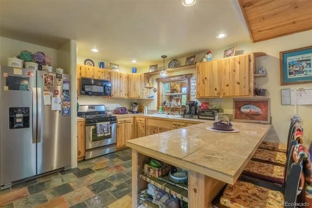 a kitchen with stainless steel appliances granite countertop a sink refrigerator and cabinets