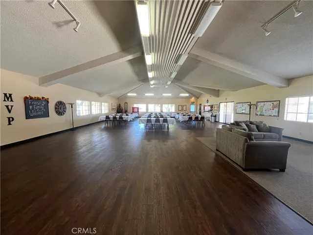 a living room with couches and kitchen view with wooden floor