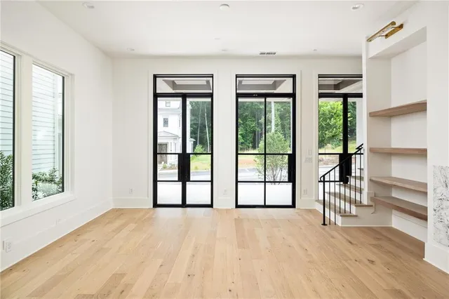 a view of an empty room with a window and wooden floor