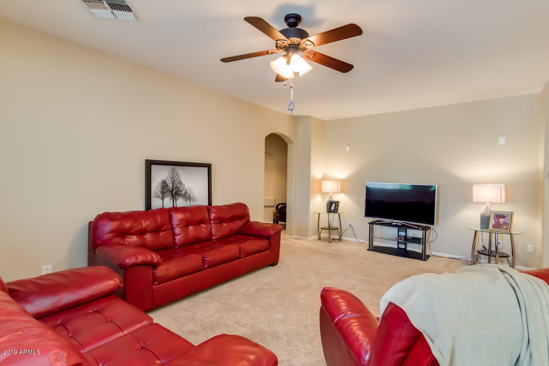 16528 West Sherman Street Goodyear, AZ 85338 - Photo 14 of 33 a living room with furniture a chandelier and a flat screen tv