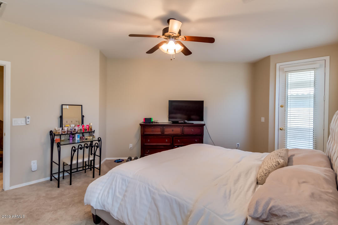 16528 West Sherman Street Goodyear, AZ 85338 - Photo 20 of 33 a bedroom with a bed and a chandelier