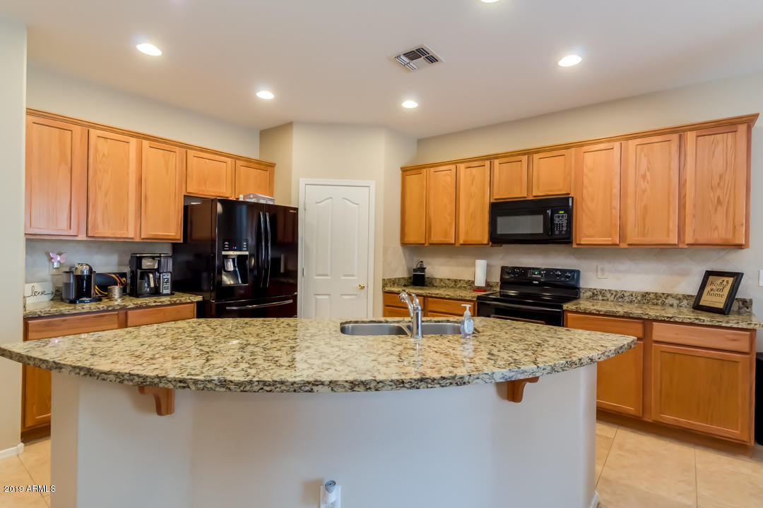 16528 West Sherman Street Goodyear, AZ 85338 - Photo 5 of 33 a kitchen with kitchen island granite countertop a sink stove and microwave