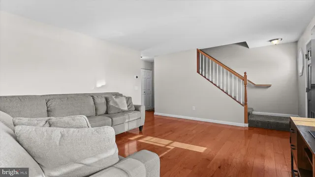 a living room with furniture and stairs with wooden floor