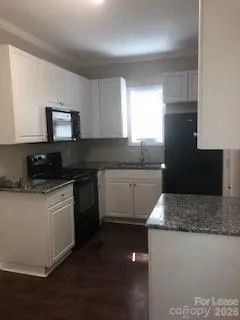 a kitchen with granite countertop white cabinets and black appliances