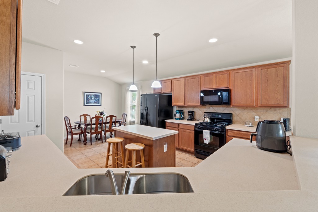 12008 Lansdowne Road Austin, TX 78754 - Photo 14 of 29 A well-lit kitchen with wood cabinetry and an island flows seamlessly into the dining area.