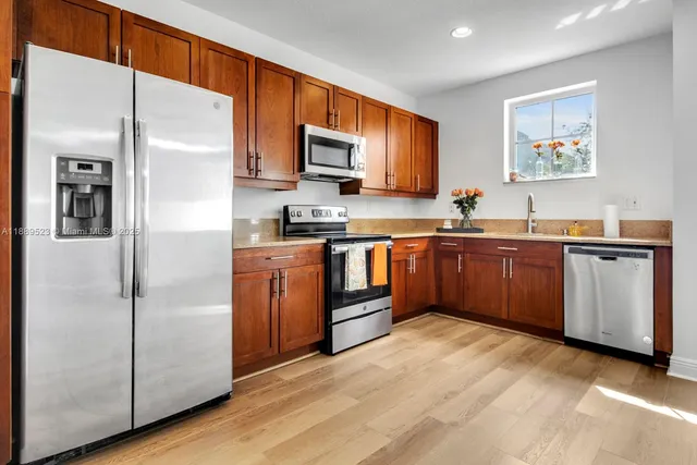 a kitchen with stainless steel appliances granite countertop a stove a sink a refrigerator with grey cabinets