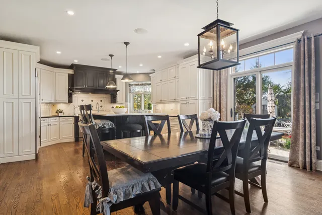 a kitchen with stainless steel appliances granite countertop a stove a sink dishwasher a dining table and chairs with wooden floor