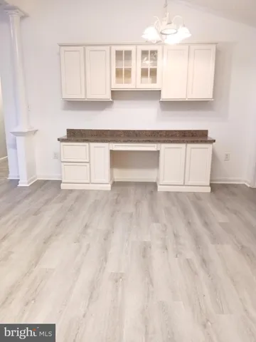 a view of a kitchen with granite countertop white cabinets and a wooden floor