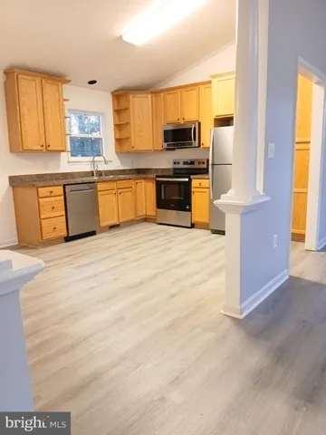 a kitchen with stainless steel appliances a stove top oven a sink a counter top space cabinets and a window