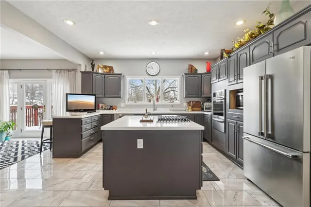 a view of a kitchen with kitchen island a counter top space a sink stainless steel appliances and cabinets