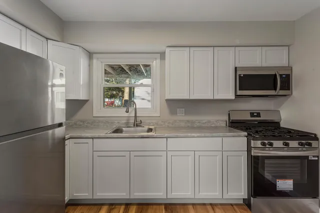 a kitchen with stainless steel appliances granite countertop a refrigerator stove a sink and dishwasher with wooden floor