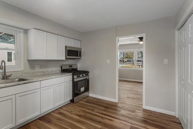 a view of a livingroom with wooden floor and a refrigerator