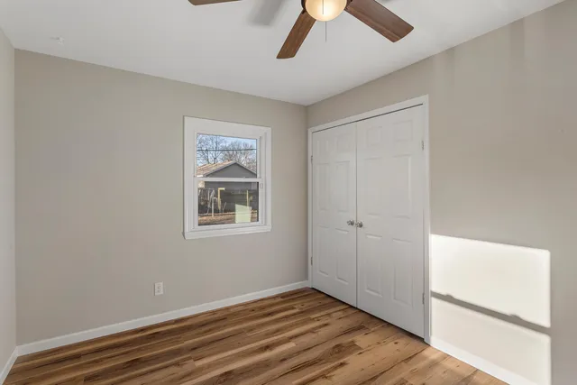a view of an empty room with wooden floor and a window