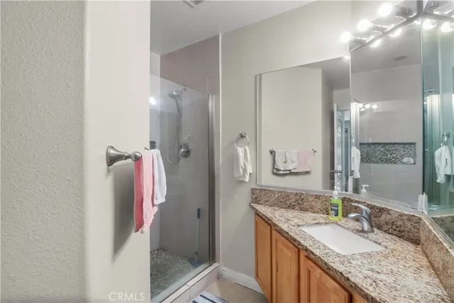 a bathroom with a granite countertop shower sink and mirror
