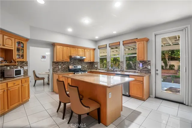 a kitchen with stainless steel appliances granite countertop a stove a sink a oven with a dining table and chairs