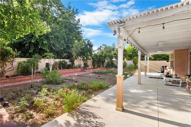 a view of a patio with table and chairs potted plants and floor to ceiling window and wooden fence