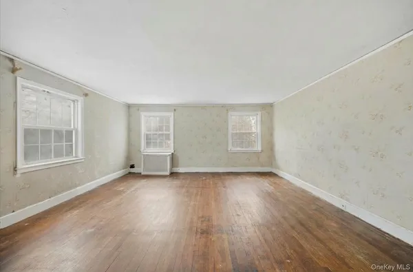 a view of an empty room with wooden floor and windows