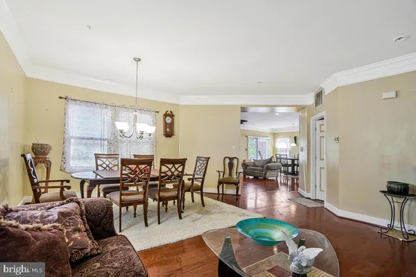 a room with chandelier fan and wooden furniture