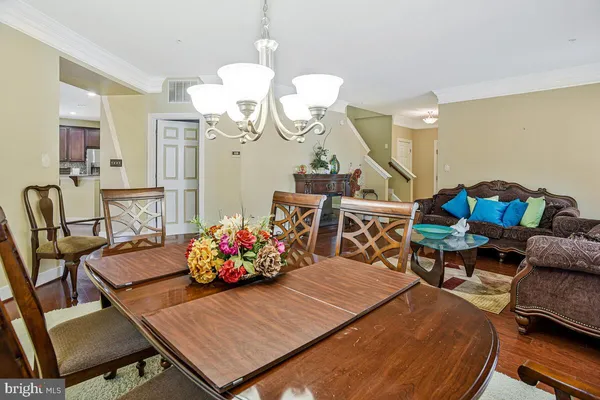 a kitchen with stainless steel appliances granite countertop a sink a stove a refrigerator cabinets and a dining table with wooden floor