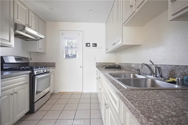 a kitchen with granite countertop a sink stove and cabinets