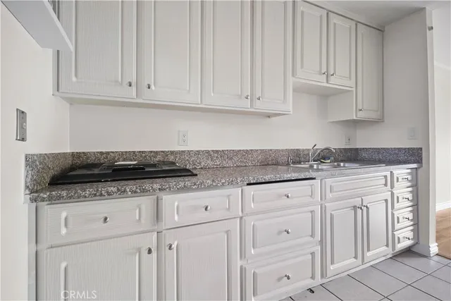 a kitchen with granite countertop white cabinets and a sink