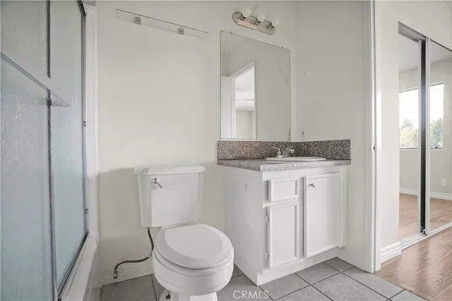 a bathroom with a granite countertop sink a toilet and a mirror