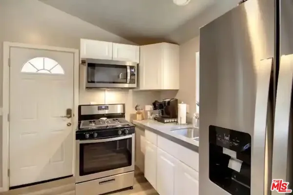 a kitchen with granite countertop white cabinets and black appliances