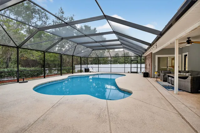 a view of a swimming pool with a patio and a backyard