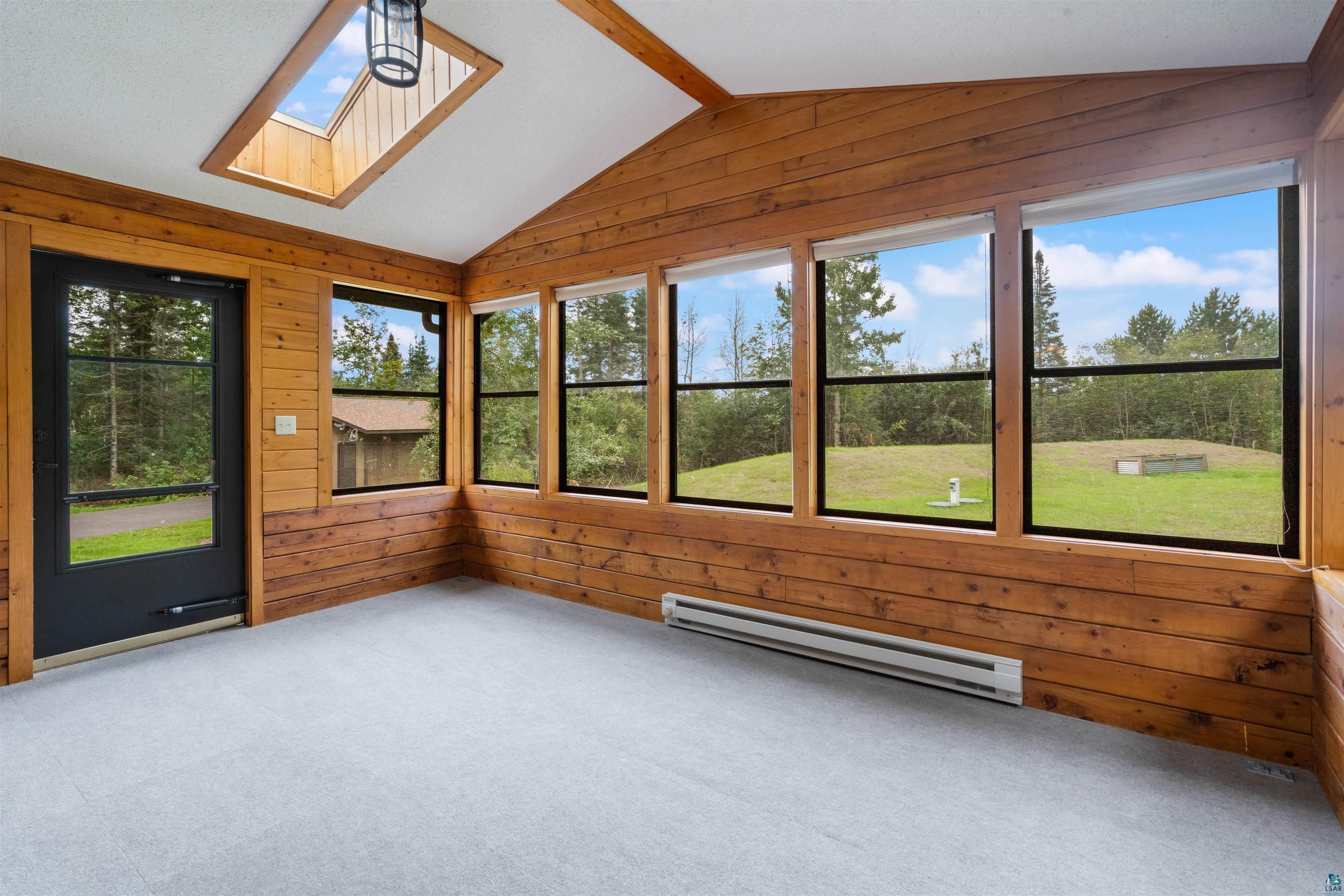 5373 Lester River Road Duluth, MN 55804 - Photo 20 of 39 Vaulted ceiling sunroom with wood-paneled walls and light-toned carpeting