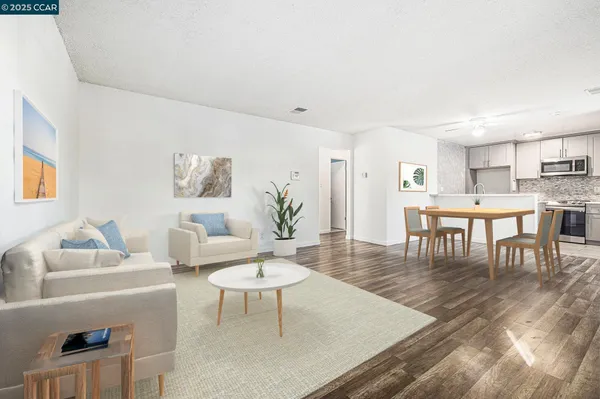 a living room with furniture a table and kitchen view