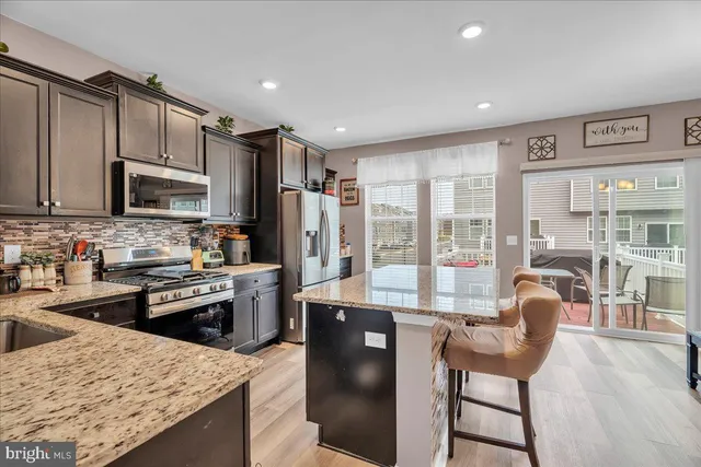 a kitchen with stainless steel appliances granite countertop a stove top oven a sink dishwasher a dining table and chairs with wooden floor